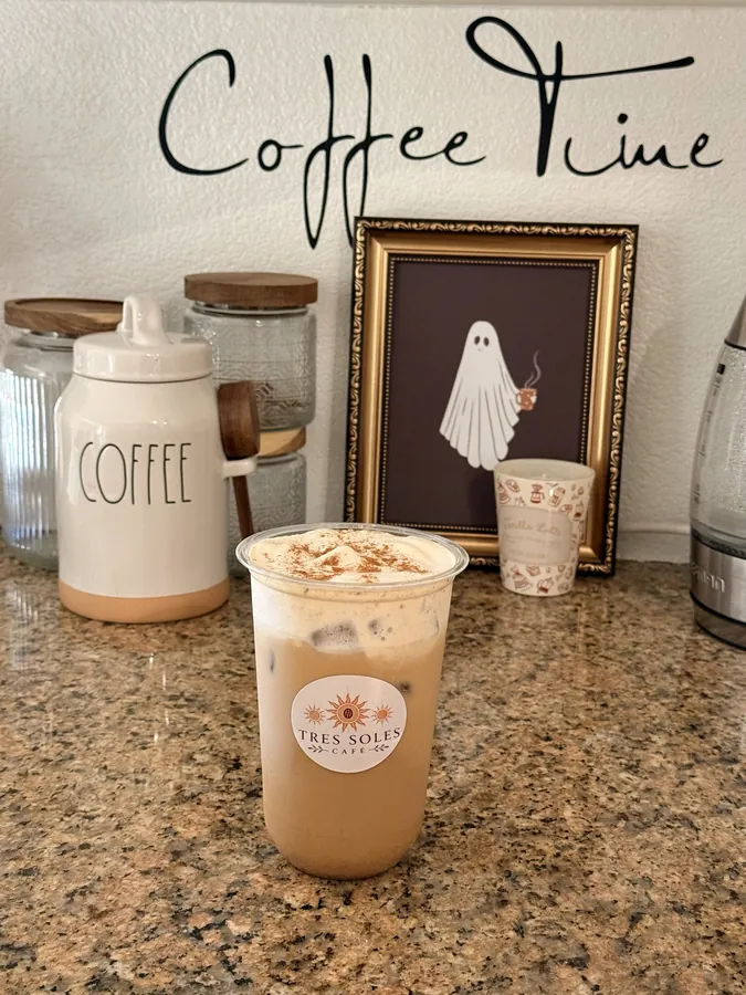 An iced latte with cinnamon cold foam on the coffee counter